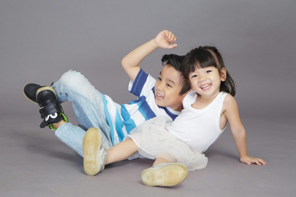 Two children playing joyfully on a studio backdrop, showcasing happiness and togetherness.