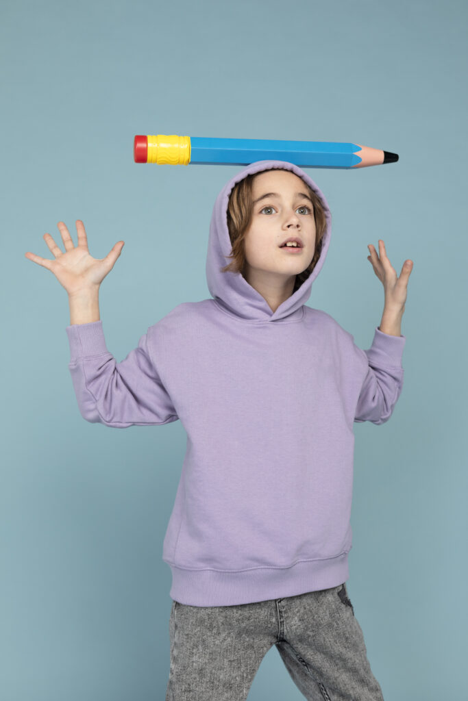 portrait teen boy carrying with big pencil his head